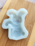 A light blue Artesao Silicone Cookie Mold of a bunny on a wood board.