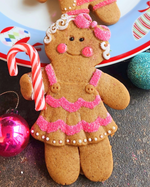 Decorative gingerbread cookies with pink icing and candy canes on a festive plate.
