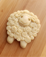 unbaked lamb shaped cookie with swirling pattern design on its wool sitting on a light wood board