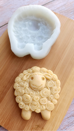 Sheep-shaped Artesao Silicone Cookie Mold cookie mold on a wooden board with an unbaked sheep-shaped cookie made from it next to it.