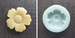 Unbaked flower cookie next to blue silicone mold made with it on gray slate background