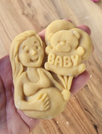 Unbaked cookie of a pregnant woman holding a teddy bear balloon with "BABY" on it